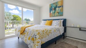 Een slaapkamer met een bed, een raam, een balkon en een schilderij aan de muur.