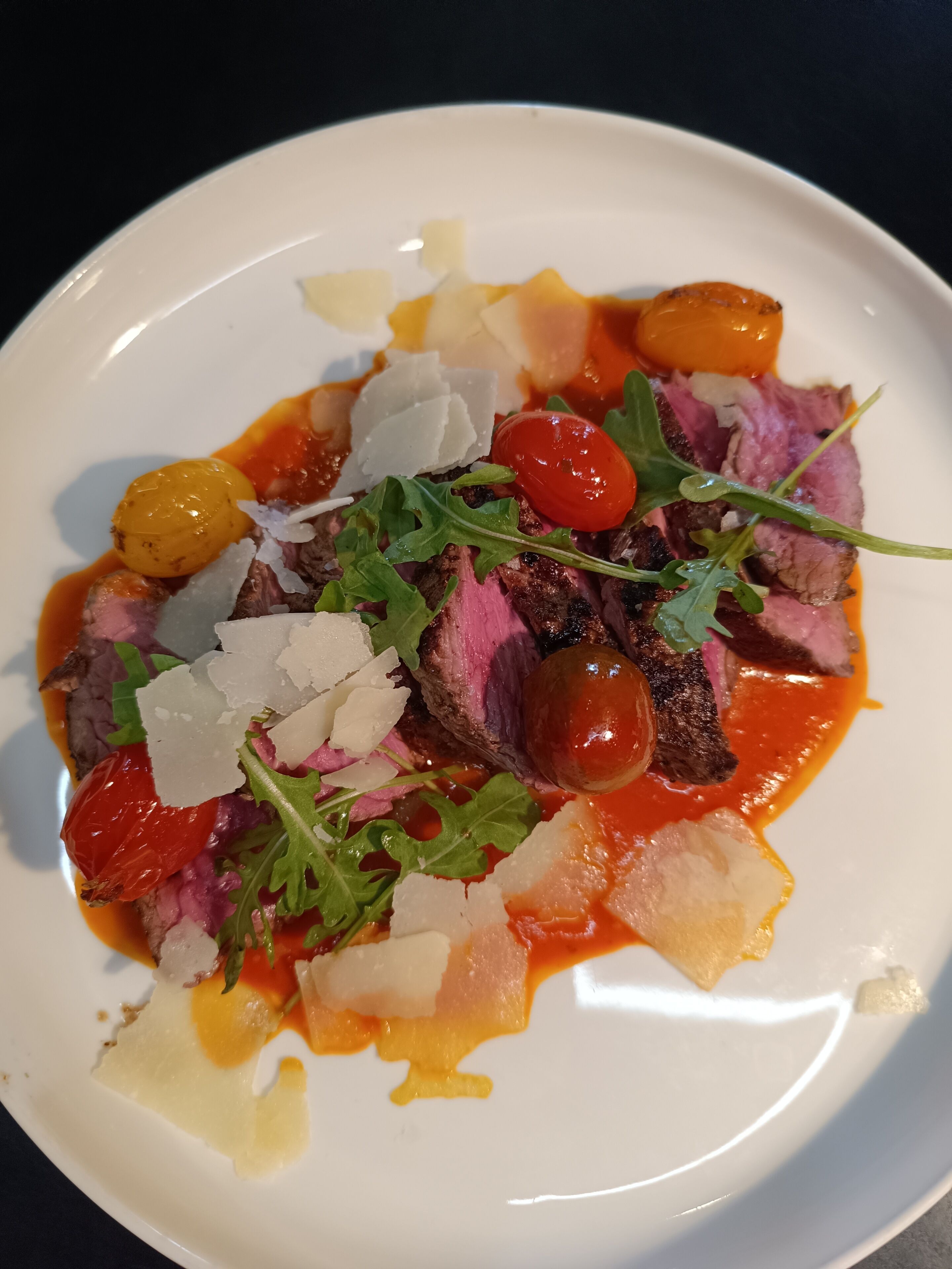 A plate of food with steak, cherry tomatoes, and cheese.