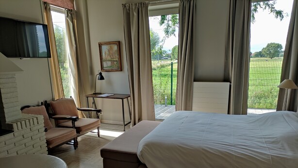 A bedroom with a large bed, a desk, a chair, and a TV mounted on the wall. - ' t Bed en tafel (Avelgem)