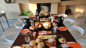 A breakfast buffet with various pastries, fruits, and beverages on a wooden table. - ' t Bed en tafel (Avelgem)