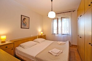 Quarto de hotel com cama, abajures, um quadro na parede, janela com cortinas e um guarda-roupa.