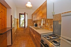 Uma cozinha com armários de madeira, fogão a gás, pia e geladeira.