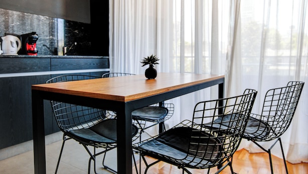 A modern kitchen with a wooden table and black wire chairs, a coffee maker, and a vase with a plant on the counter. - Moderno Studio en Palermo Hollywood C3D (Buenos Aires)