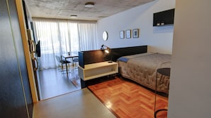 A hotel room with a bed, a desk, a chair, a TV, and a bedside table. - Moderno Studio en Palermo Hollywood C3D (Buenos Aires)