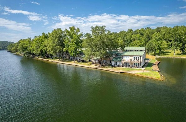 A lakeside property with a large house, a dock, and a boat.