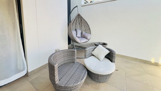 Un balcon agrémenté de meubles en osier, notamment une chaise et une petite table.