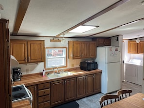 A compact kitchen with wooden cabinets, a white refrigerator, a microwave, and a sink.