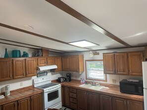 A kitchen with wooden cabinets, a white stove, a sink, and a window.