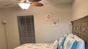 A bedroom with a bed, a wooden dresser, a ceiling fan, and a window with blinds. - Charming 3-bedroom, 2 bath condo, fully furnished in marvelous St. Simons Island (St. Simons Island)