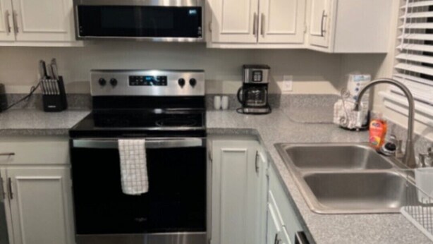 A modern kitchen with white cabinets, stainless steel appliances, a microwave, oven, coffee maker, and a dishwasher. - Charming 3-bedroom, 2 bath condo, fully furnished in marvelous St. Simons Island (St. Simons Island)