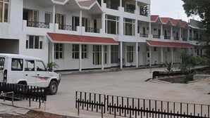 A multi-story building with a flat roof and large windows. There is a white vehicle parked in front. - Tikkar Taal Morni Hills (Panchkula)