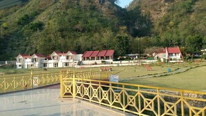 A hotel with multiple buildings, a fenced courtyard, and a mountainous backdrop. - Tikkar Taal Morni Hills (Panchkula)