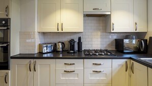 A modern kitchen with white cabinets, stainless steel appliances, and a black countertop. - Dartford - 3 Bed House- Sleeps7 - Garden (Dartford)