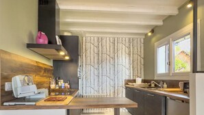 A modern kitchen with a central island, wooden wall paneling, and a window with a view.