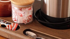A stainless steel kettle, a glass jar with a bamboo lid, and a wooden tray with a spoon. - Troiada Hotel (Gokceada)