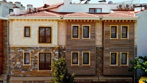 A multi-story building with a stone facade and wooden paneling. - Troiada Hotel (Gokceada)