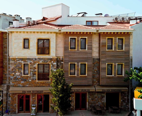 A multi-story building with a stone facade and wooden paneling. - Troiada Hotel (Gokceada)
