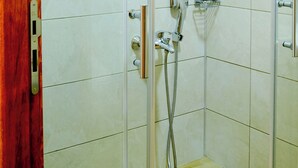 A walk-in shower with a glass door, a handheld showerhead, and a handheld shower attachment. - Troiada Hotel (Gokceada)