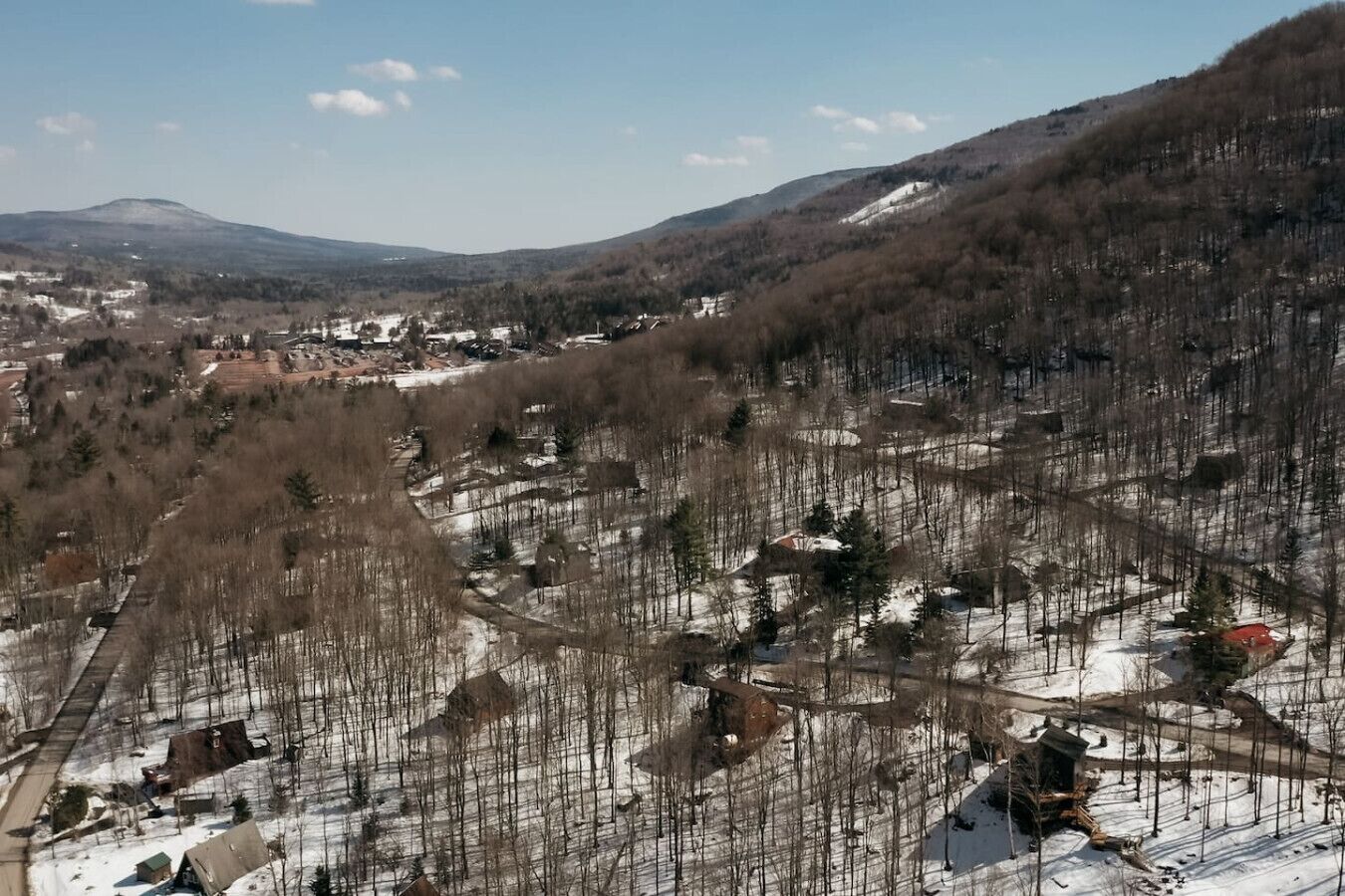 Un paysage rural parsemé de maisons, avec une route sinueuse et une montagne en arrière-plan.