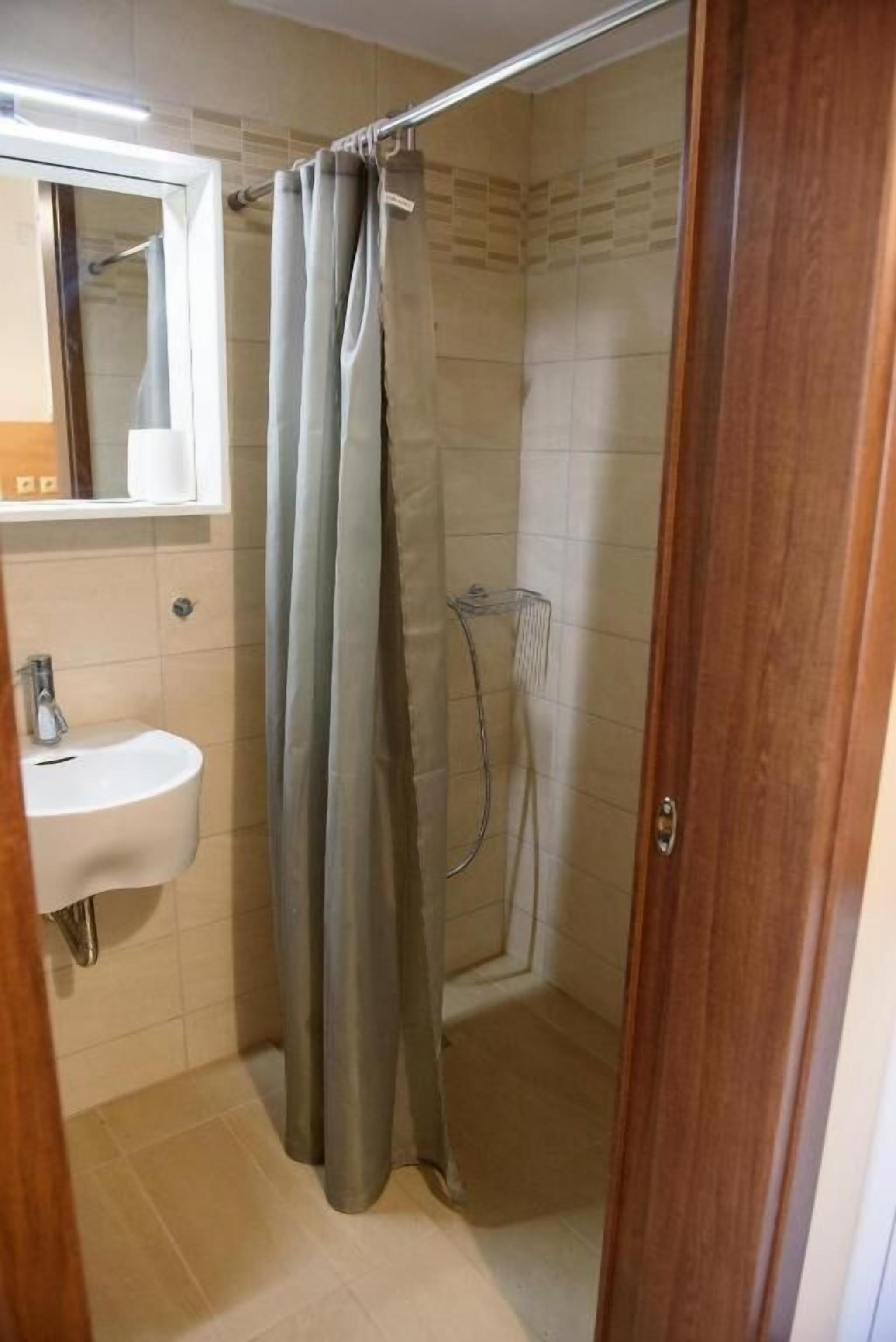 Une salle de bain avec une douche, un lavabo et un miroir.