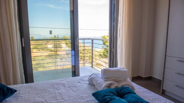 A bedroom with a bed, a balcony with a view, and a white wardrobe. - San Gerasimo Villas (Xylokastro-Evrostina)