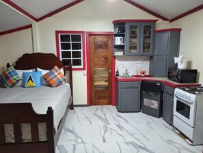 A compact hotel room with a bed, a small kitchenette, and a bathroom. - THE COZY WOODEN NEST IN LABORIE (LABORIE)