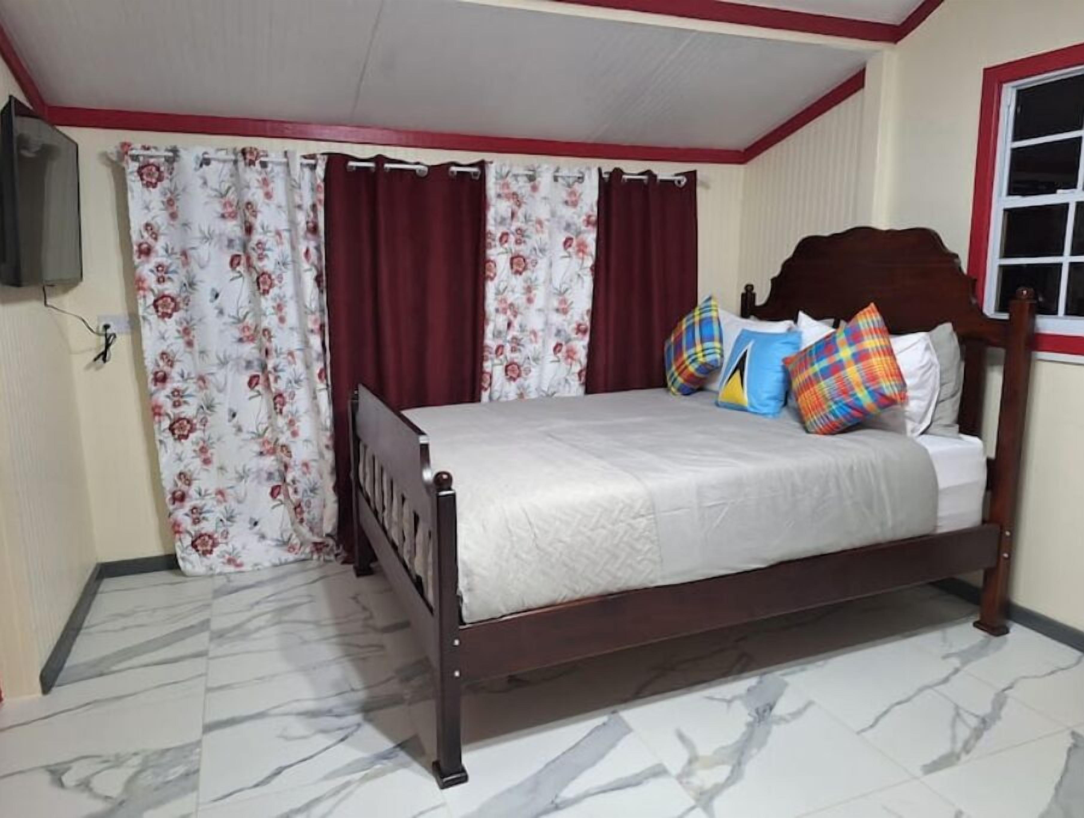 A bedroom with a bed, curtains, a window, and a TV.