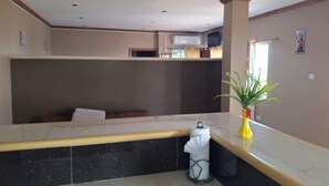Eine Hotlellobby mit einer Rezeption, einer Sitzecke und einer Pflanze auf dem Tresen.