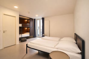 Ein Schlafzimmer mit einem Bett, einem Kleiderschrank, einem Koffer und einem Fenster mit Vorhängen.
