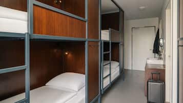 Habitación de hotel con literas, un baño pequeño y una maleta.