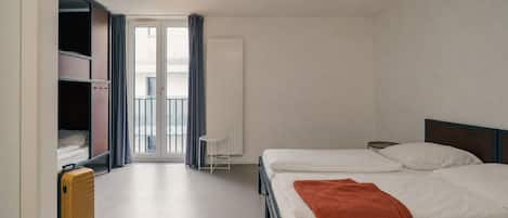 Una camera d'albergo con un letto, una valigia, una sedia e una finestra con tende.