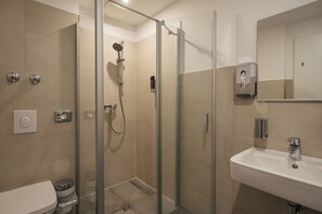 Une salle de bain moderne avec une douche à parois de verre, un lavabo blanc et un miroir.