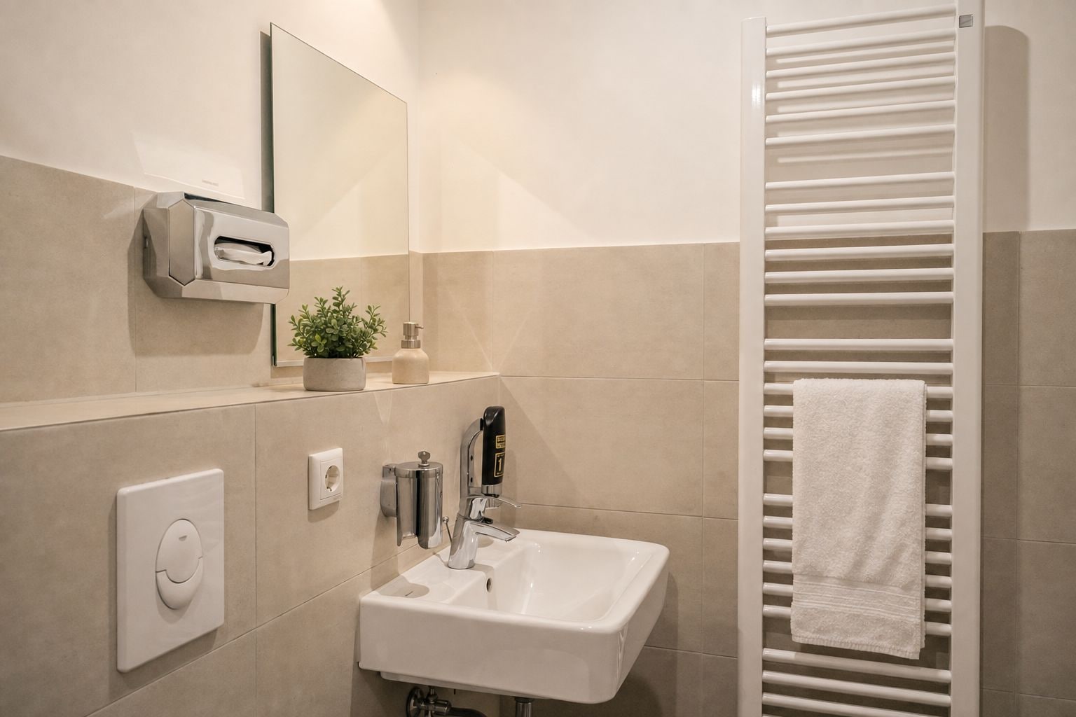 A modern bathroom with a white sink, a towel rack, a hand dryer, and a mirror.