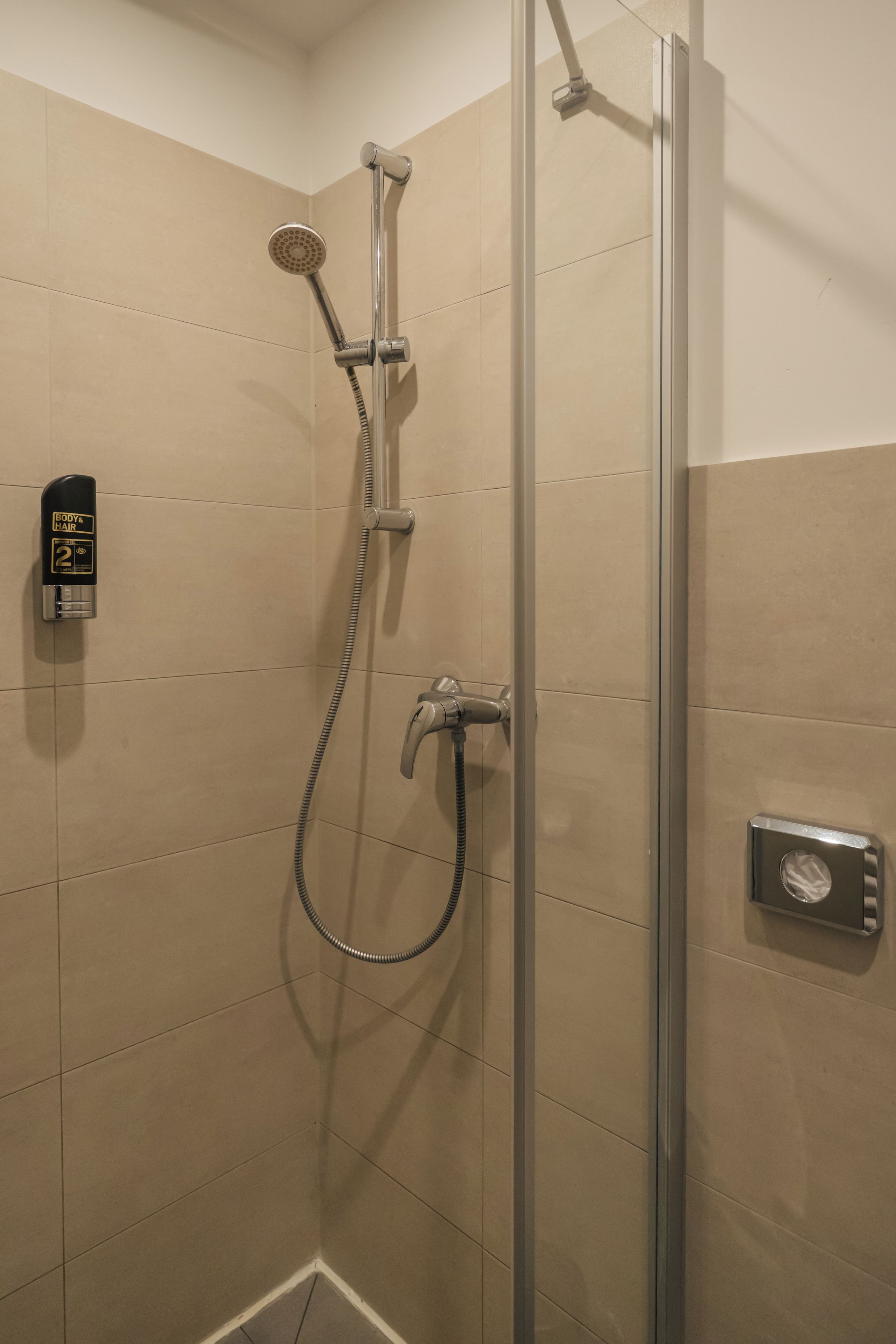 A shower with a handheld showerhead, a wall-mounted faucet, and a handheld shower hose.