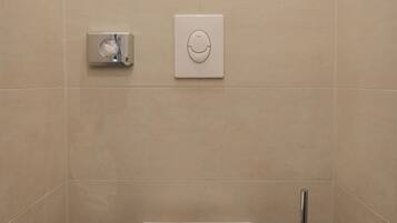 A modern bathroom with a toilet, a trash bin, and a bidet.