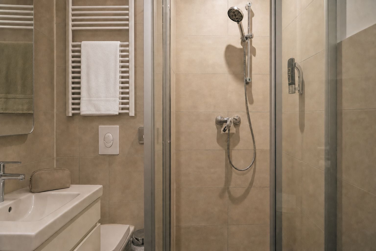 Ein modernes Badezimmer mit Duschkabine aus Glas, einem weißen Waschbecken und einem Handtuchhalter.