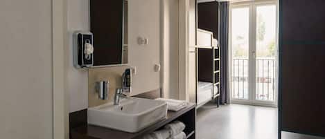 A modern bathroom with a double sink, a mirror, a towel rack, and a view of the outside through a glass door.