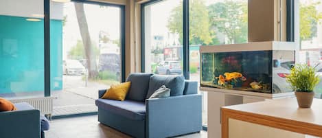 A modern interior with a sofa, a fish tank, and large windows.