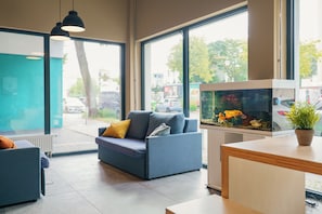 Een modern interieur met een bank, een vissenkom en grote ramen.