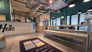 Ein moderner Hotel-Empfangsbereich mit einem 'Hello'-Schild, einer Rezeption und einer Fußmatte mit dem Schriftzug 'AR Hotels'.