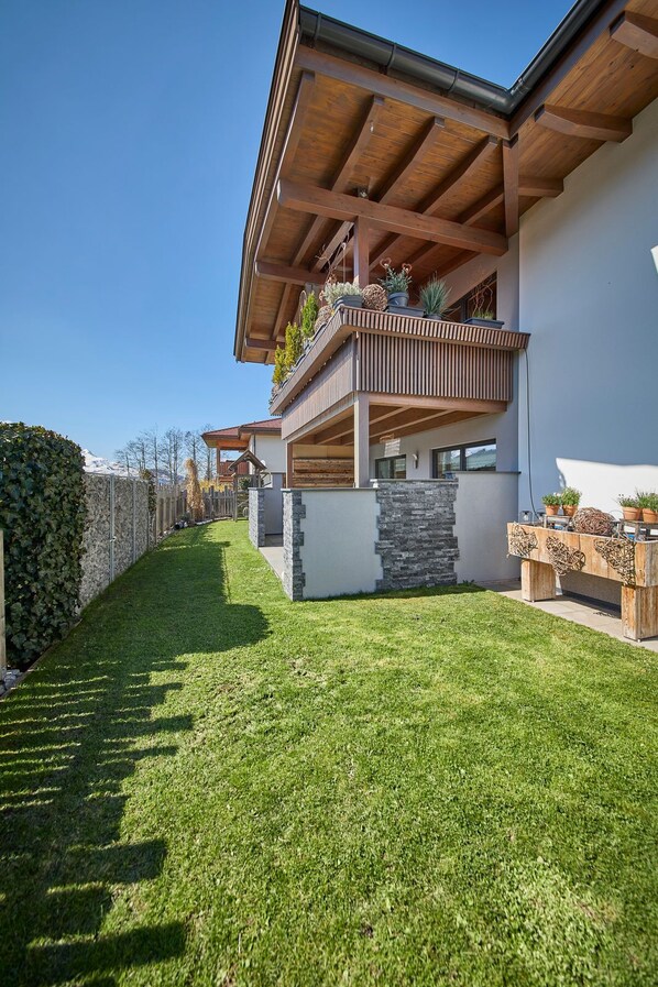 Une maison moderne dotée d’un balcon en bois, de détails en pierre et d’une pelouse bien entretenue.