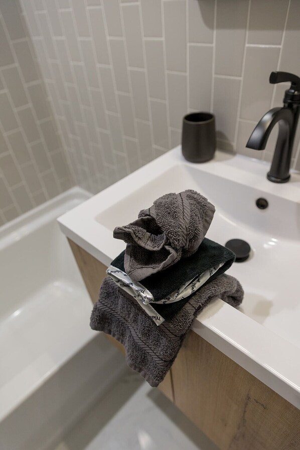 A bathroom with a white sink, a black faucet, and a towel rack holding a folded towel. - Happy Hour | Pool Table | Shuffleboard | Fire Pit (Denver)