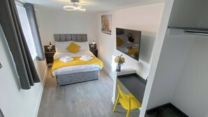 A modern hotel room with a bed, bedside table, chair, and a small desk area. - Luxury studio apartment by the station (Plymouth)