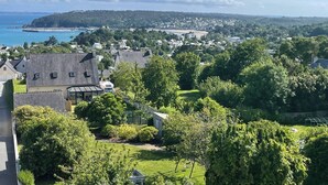 A residential area with houses, green lawns, and a distant view of a coastline. - Cocon à Crozon - Superb new apartment with view (Crozon)