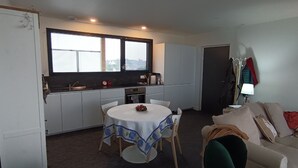 A compact living space with a kitchenette, a dining table with chairs, a sofa, and a coat rack. - Cocon à Crozon - Superb new apartment with view (Crozon)