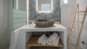 A bathroom with a stone sink, a mirror, a wooden shelf with towels, and a wooden ladder. -  Deluxe apartment with panoramic sea view located on the hill of Provatas (Milos)
