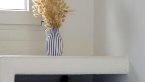 A blue storage unit with a handle, a white shelf above it, and a vase with dried flowers on the shelf. -  Deluxe apartment with panoramic sea view located on the hill of Provatas (Milos)