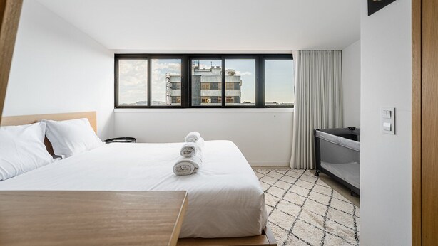 Habitación de hotel con cama, escritorio, televisor y ventana con vistas a la ciudad.