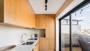 Una cocina moderna con armarios de madera, un lavamanos de acero inoxidable y un amplio ventanal con vistas a un balcón.