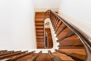 Un escalier en bois avec une rampe métallique et un mur blanc.